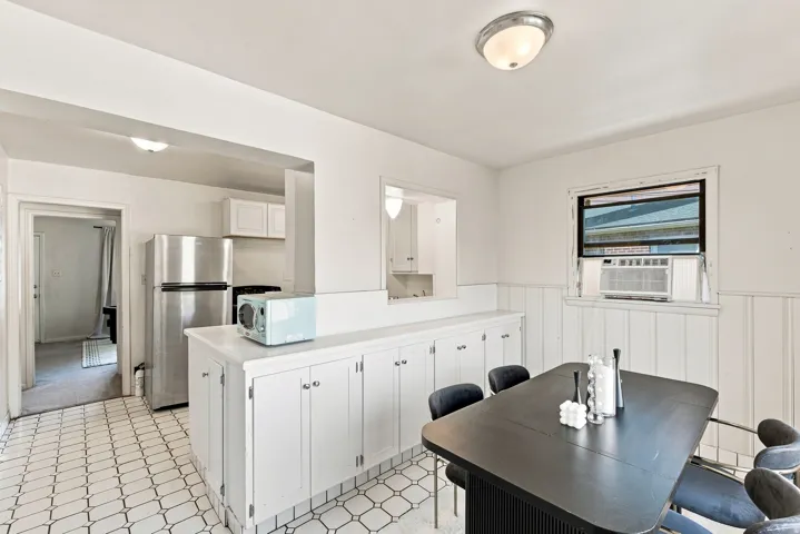 Kitchen and dining area featuring white cabinetry, a built-in window air conditioning unit, and patterned tile flooring