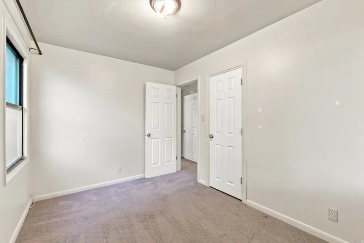 Neutral wall tones, carpet flooring, a window with trim, and a ceiling light fixture