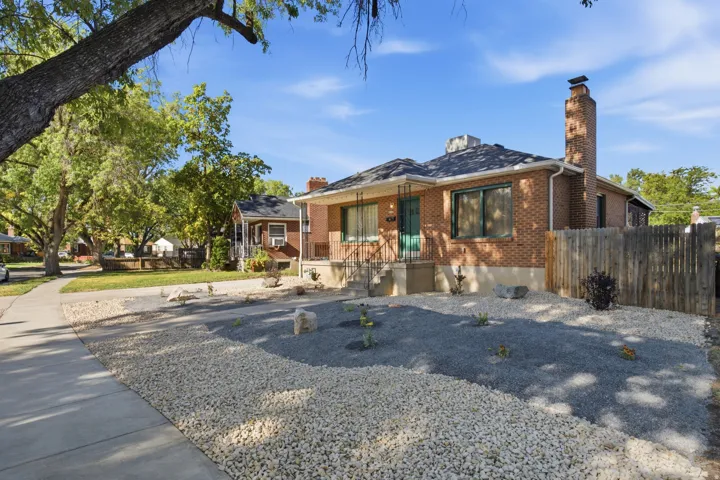 Brick exterior with a prominent chimney, covered front porch, and a gravel front yard