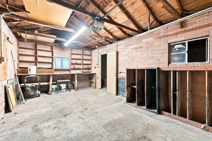 Exposed brick walls, concrete flooring, built-in shelving, and a wood beam ceiling