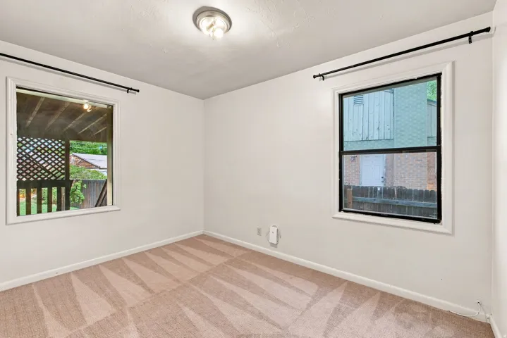 Recessed ceiling light fixture, white painted walls, two windows with black trim, and patterned carpet