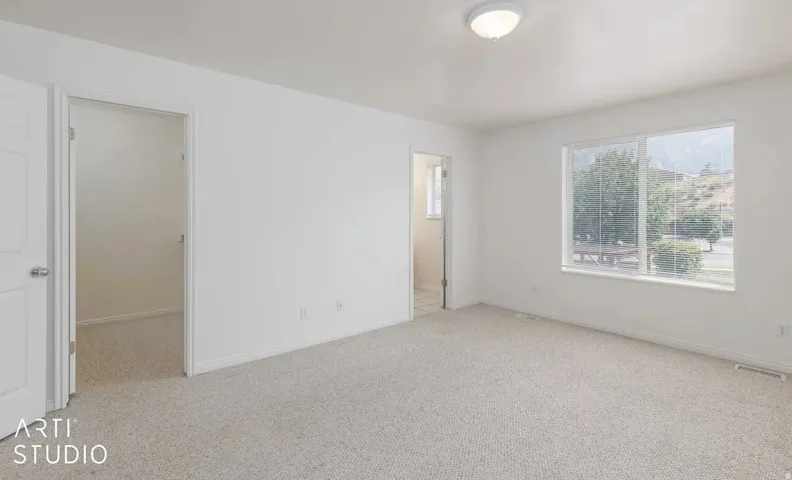 Neutral-toned carpeting, white walls, and a flush-mount ceiling light