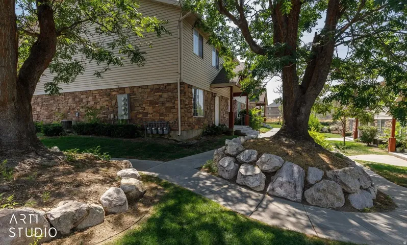 Exterior with stone veneer siding, horizontal vinyl siding, and mature trees