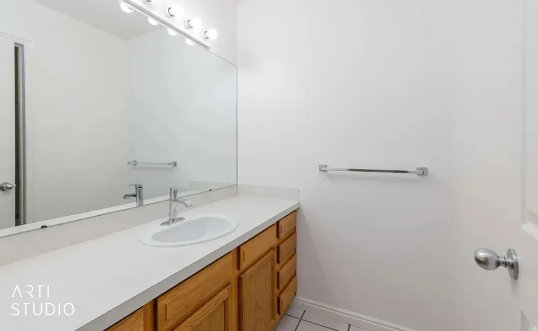 White countertop with integrated sink, wood-finish cabinetry, and chrome faucet