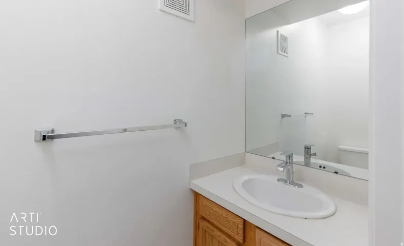Vanity with wood-finish cabinetry, integrated sink, chrome faucet, and expansive mirror