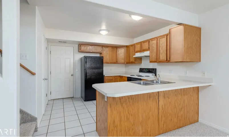 Kitchen featuring wood cabinetry, white countertops, a double basin sink, and tile flooring
