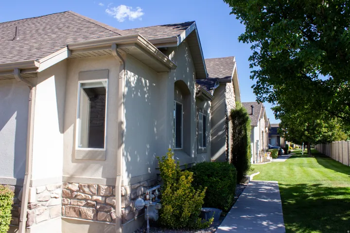 Stucco exterior with stone accent, brand new asphalt shingle roof, and white-framed windows. Front faces a grass area with mountain views.