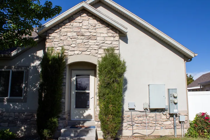 Exterior with stone and stucco finishes, arched entryway, and mature landscaping