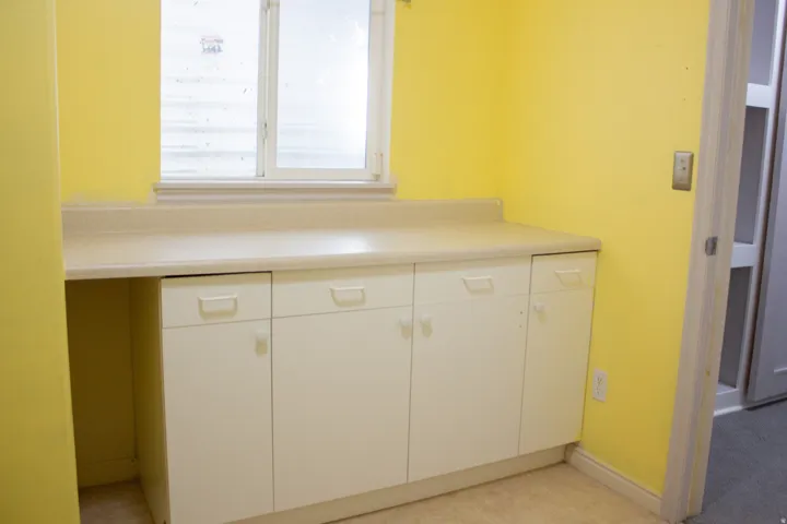 White cabinetry with a functional countertop space, and a window for natural light