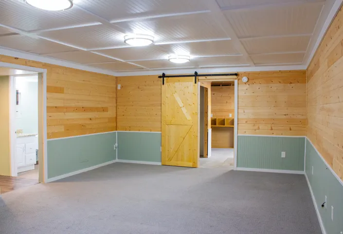 Wood-paneled walls with beadboard wainscoting, a paneled ceiling with flush-mount lighting, and a sliding barn door lading to flex area.