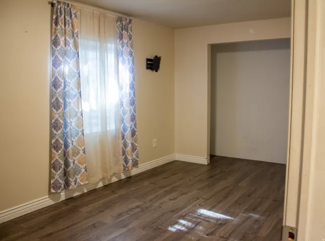 laminate flooring, neutral wall tones, white trim, and closet with built in shelves
