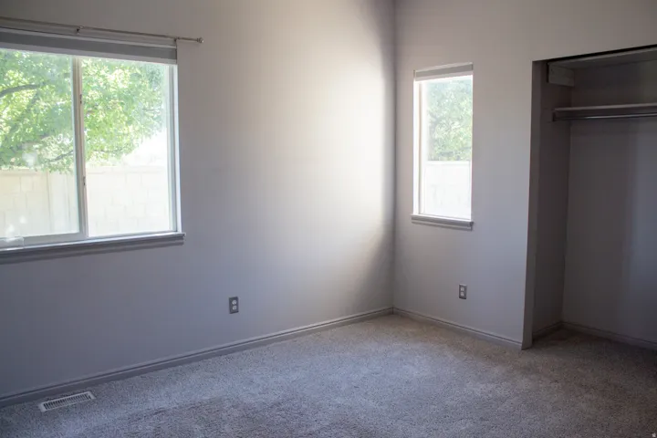 Secondary bedroom with wall-to-wall carpeting, featuring a wide window and an additional vertical window.
