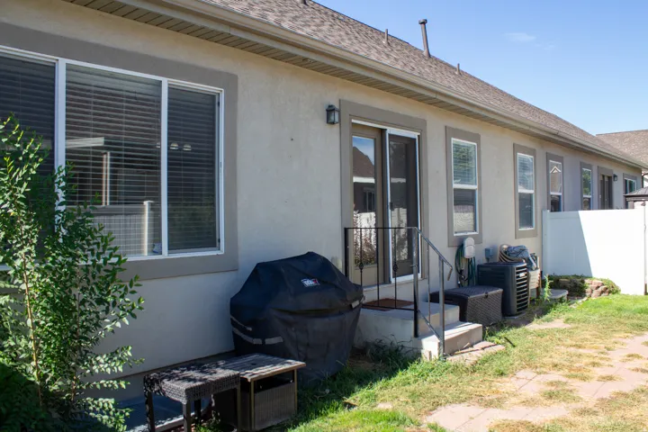 Stucco exterior with multiple windows, and a private brick paver patio featuring steps with a handrail
