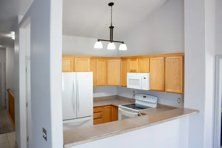 Kitchen featuring light wood cabinetry, white appliances, and a breakfast bar