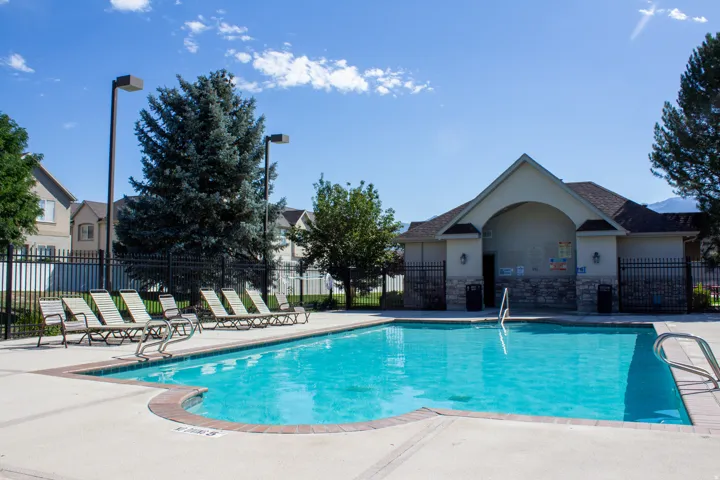 Outdoor fenced swimming pool with bathhouse containing restrooms and showers.