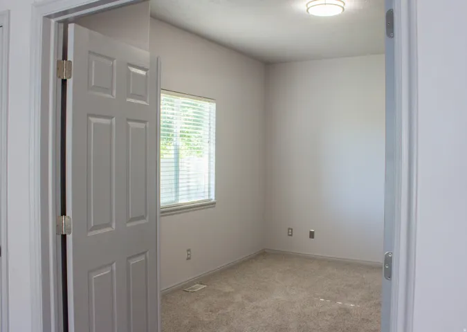Office space featuring window with blinds,  neutral wall color, and carpeted flooring