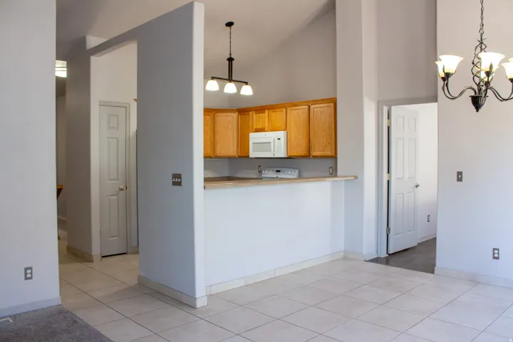 Vaulted ceiling with an exposed beam, kitchen with wood-finish cabinetry, pantry, built-in microwave, and a breakfast bar