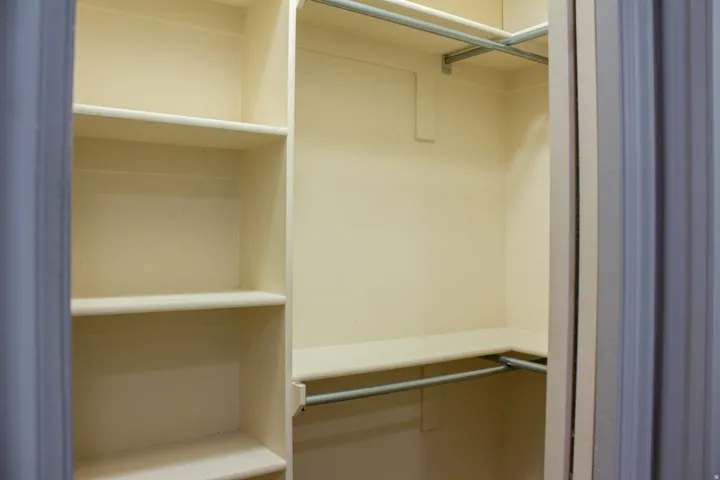 Walk-in closet of primary bedroom with built-in shelving and integrated hanging rods