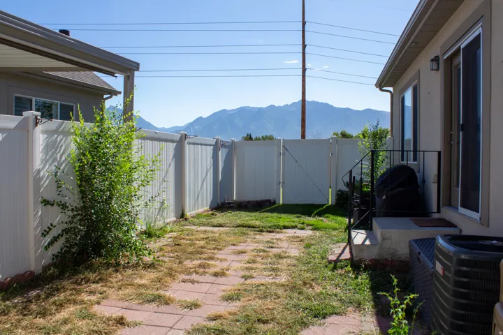 Backyard featuring a privacy fence, brick paver patio, new A/C unit, covered window wells, mountain views.