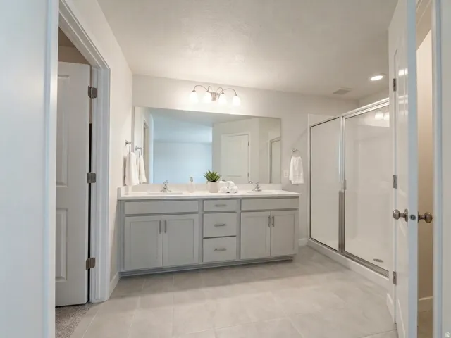 Dual vanity with light gray cabinetry, white countertops, and chrome fixtures