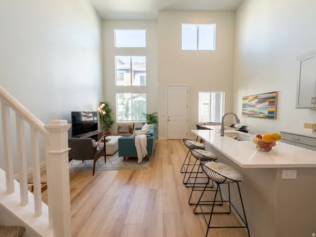 Expansive living area with high ceilings, multiple windows, and wood-finish flooring