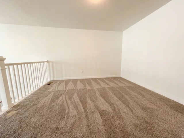 Open loft area with neutral carpet and white walls