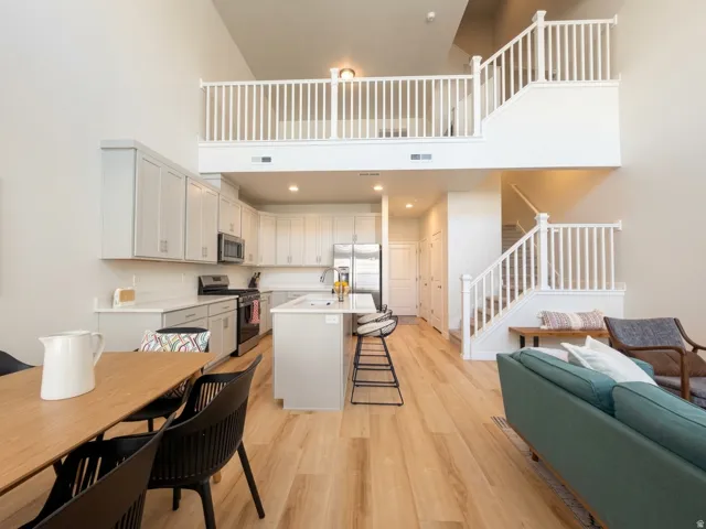 Open concept living area with high ceilings, light wood-finish flooring, and white painted balusters