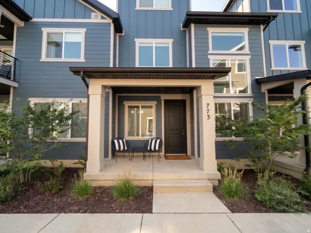 Contemporary exterior with blue siding, white window trim, a covered porch, and a dark entry door