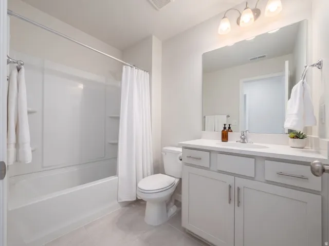 Bathroom featuring a tub/shower combination, white vanity with integrated sink, light-colored countertop, and a large wall mirror