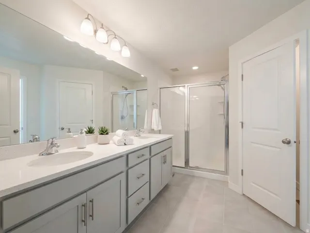 Double vanity with undermount sinks, light-toned countertops, and gray cabinetry