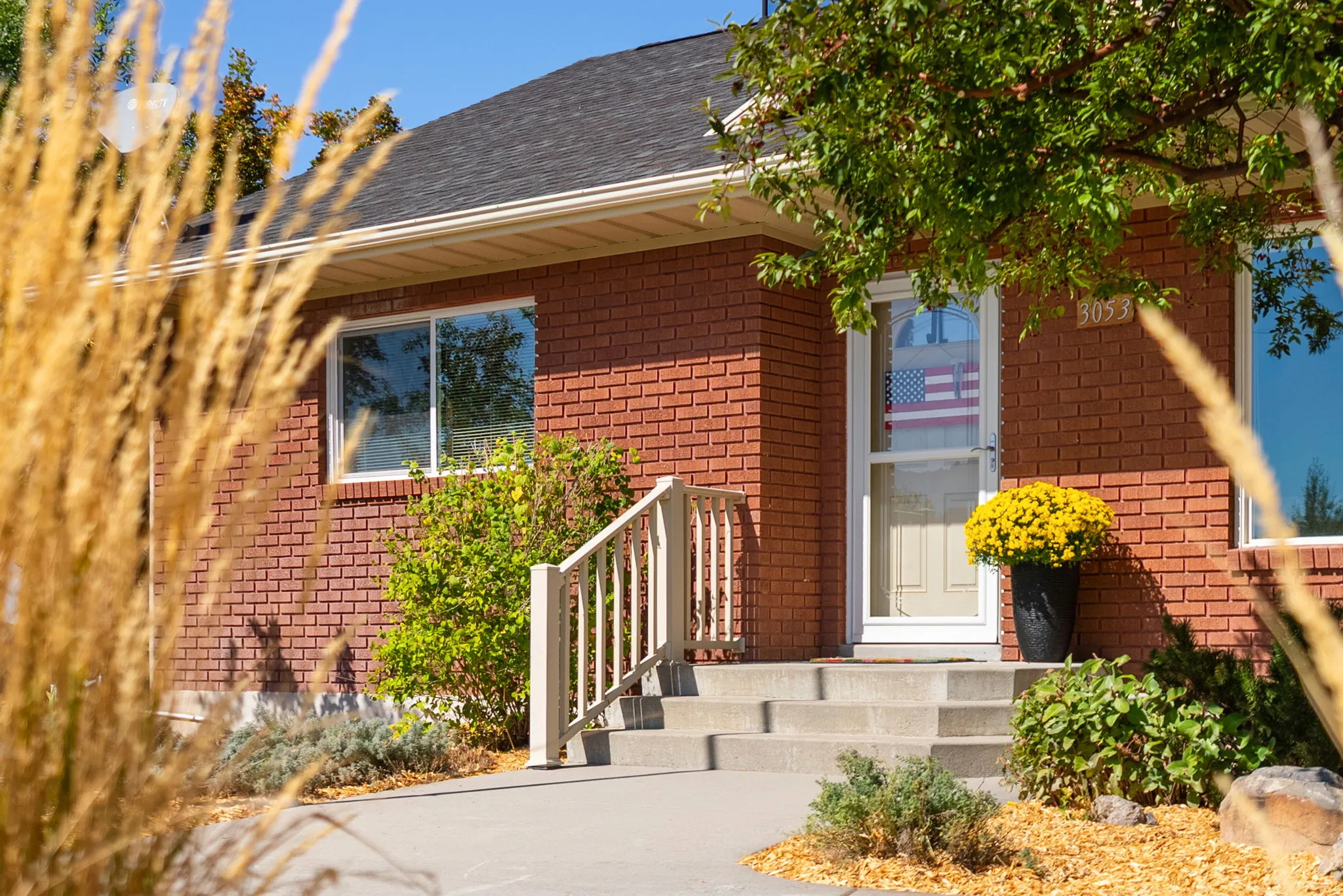 Brick exterior with a dark shingle roof, concrete porch and steps, and a white storm door