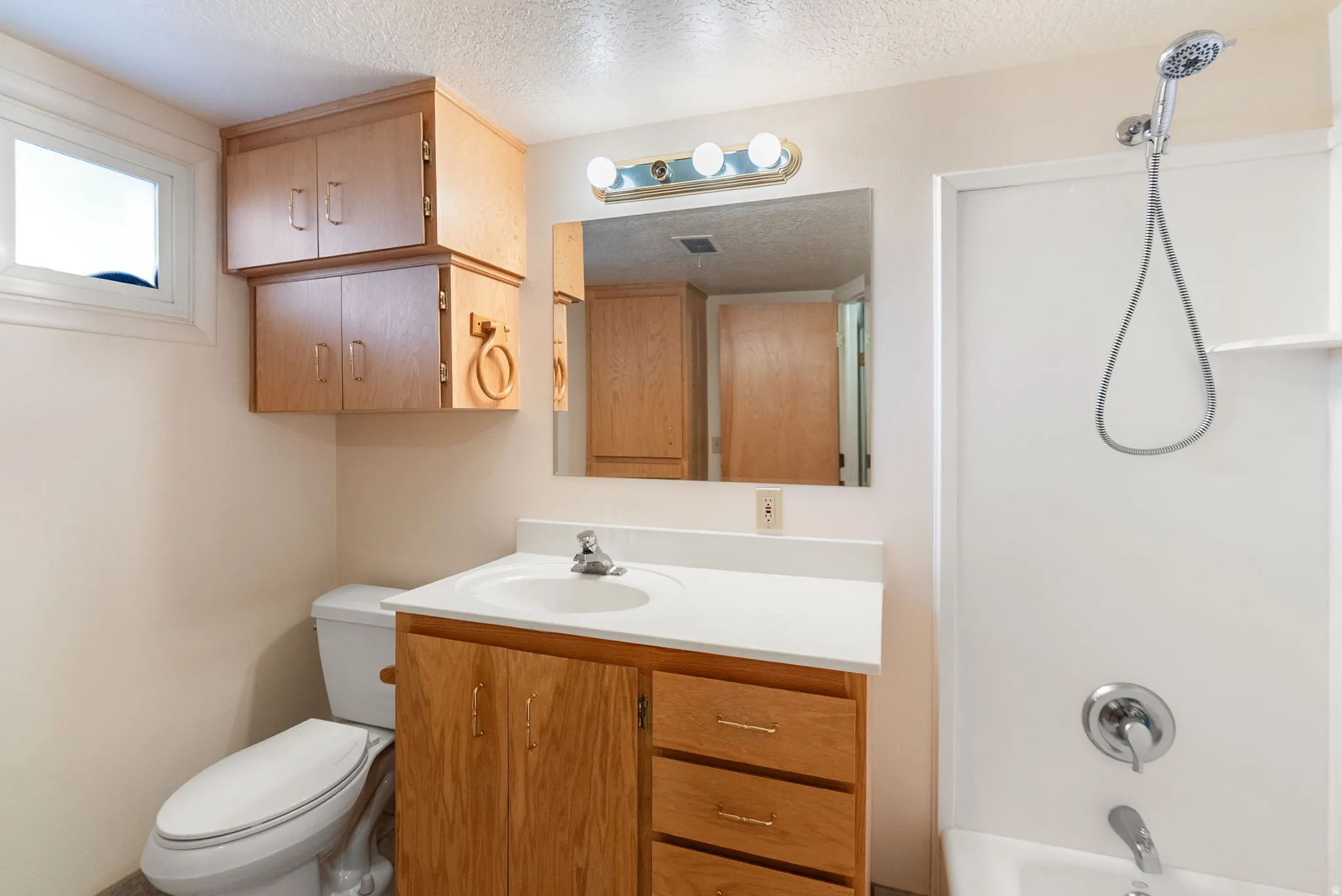 Bathroom featuring a wood-finish vanity with an integrated sink, white countertop, and matching wood-finish wall-mounted cabinetry
