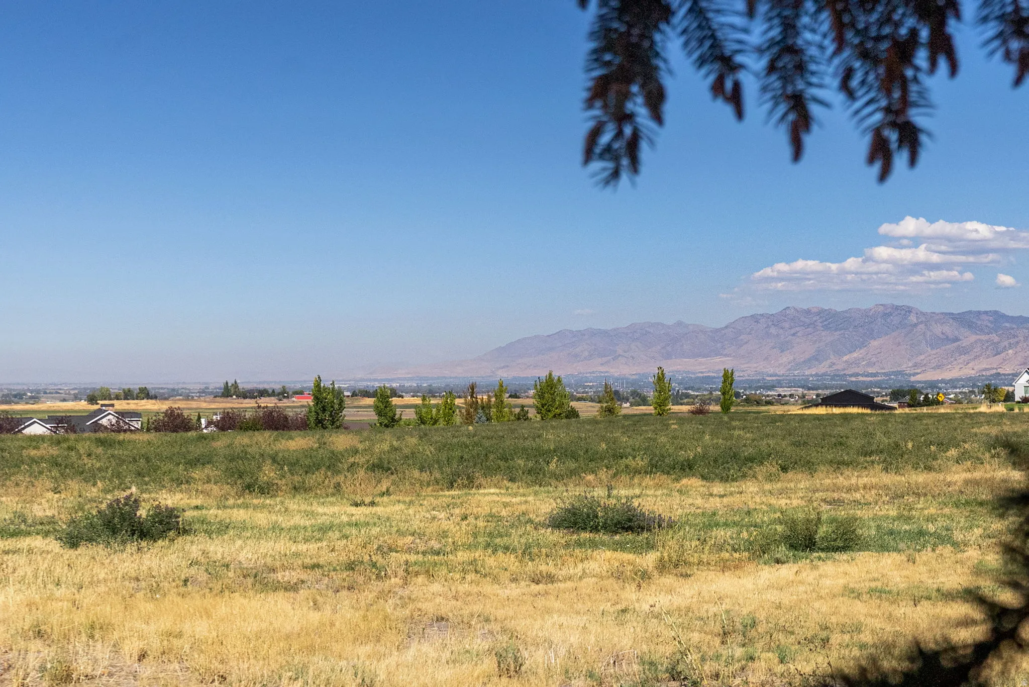 Expansive rural landscape with distant mountain ranges and scattered residential structures