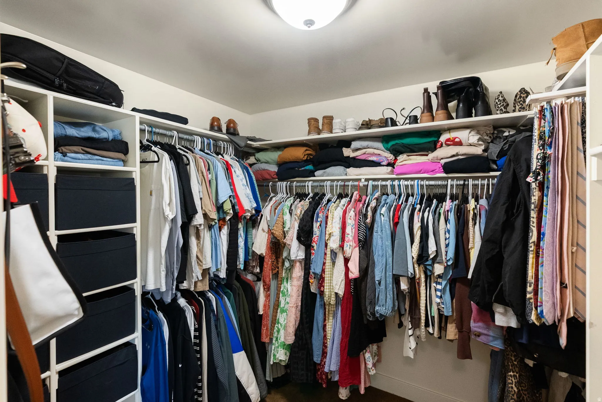 Built-in closet system with shelving, hanging rods, and an overhead light fixture
