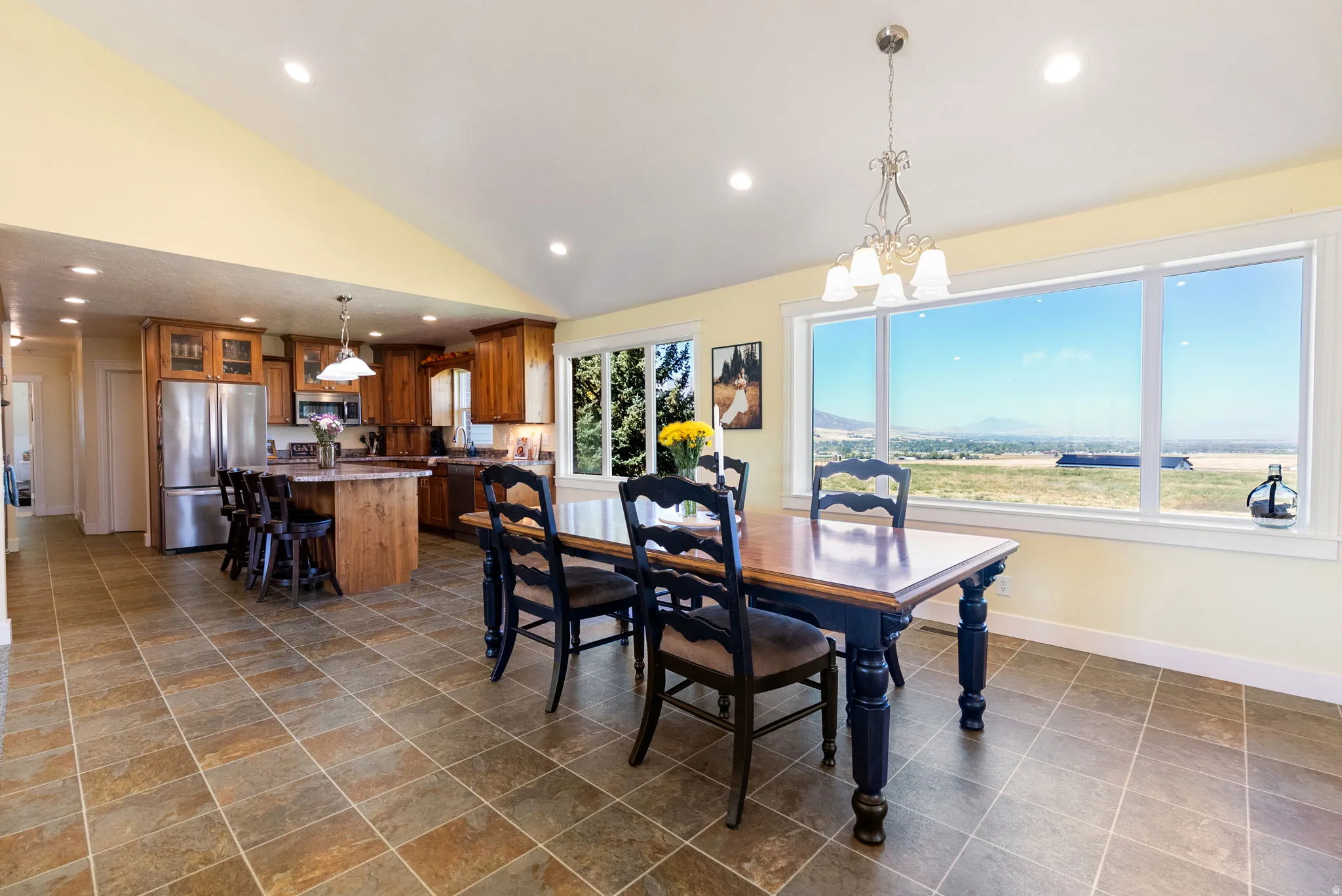Vaulted ceiling, recessed lighting, tile flooring, kitchen island with seating, and large windows