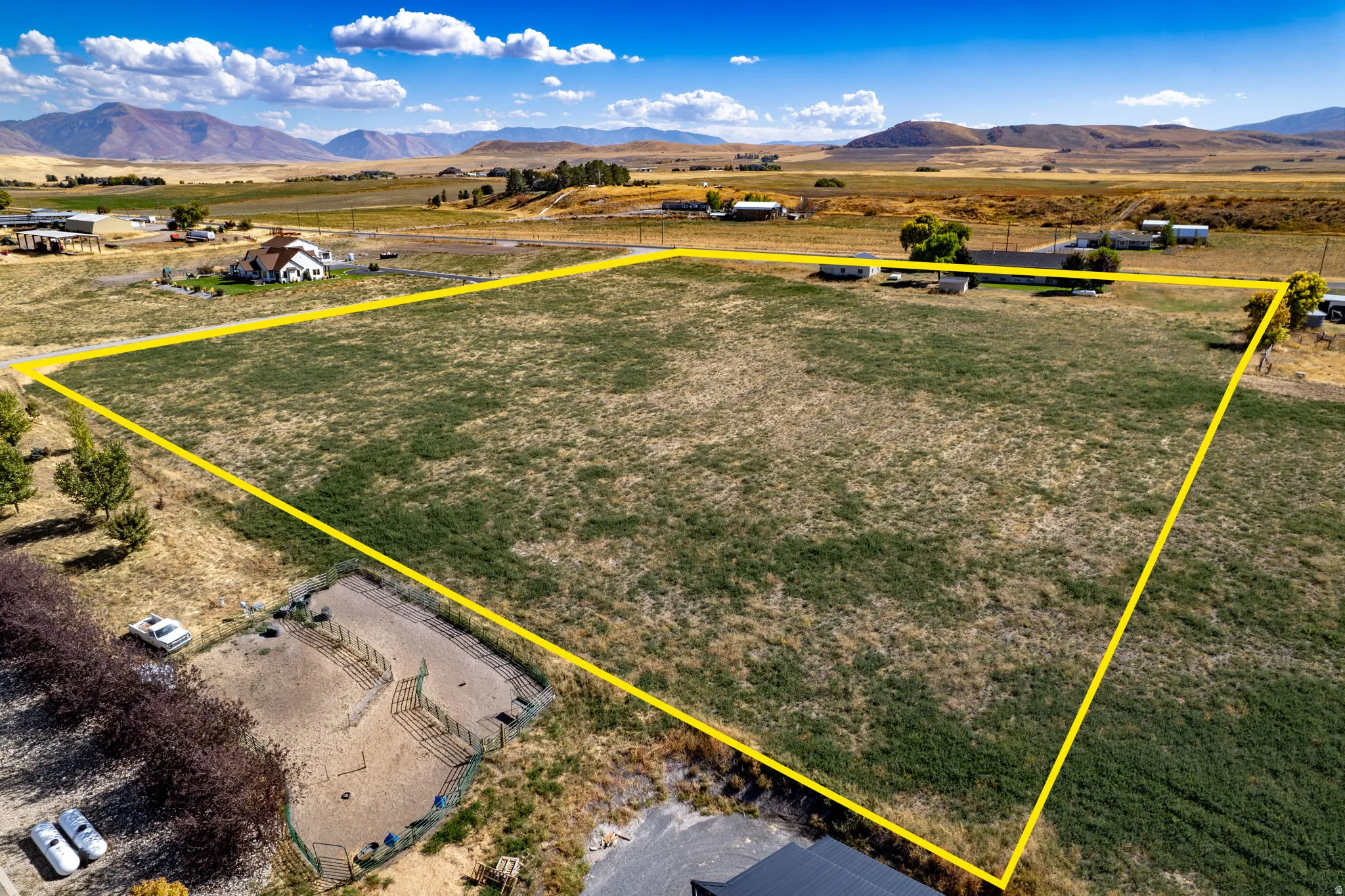 Expansive open land with a mountainous backdrop, featuring a defined property boundary and surrounding rural landscape