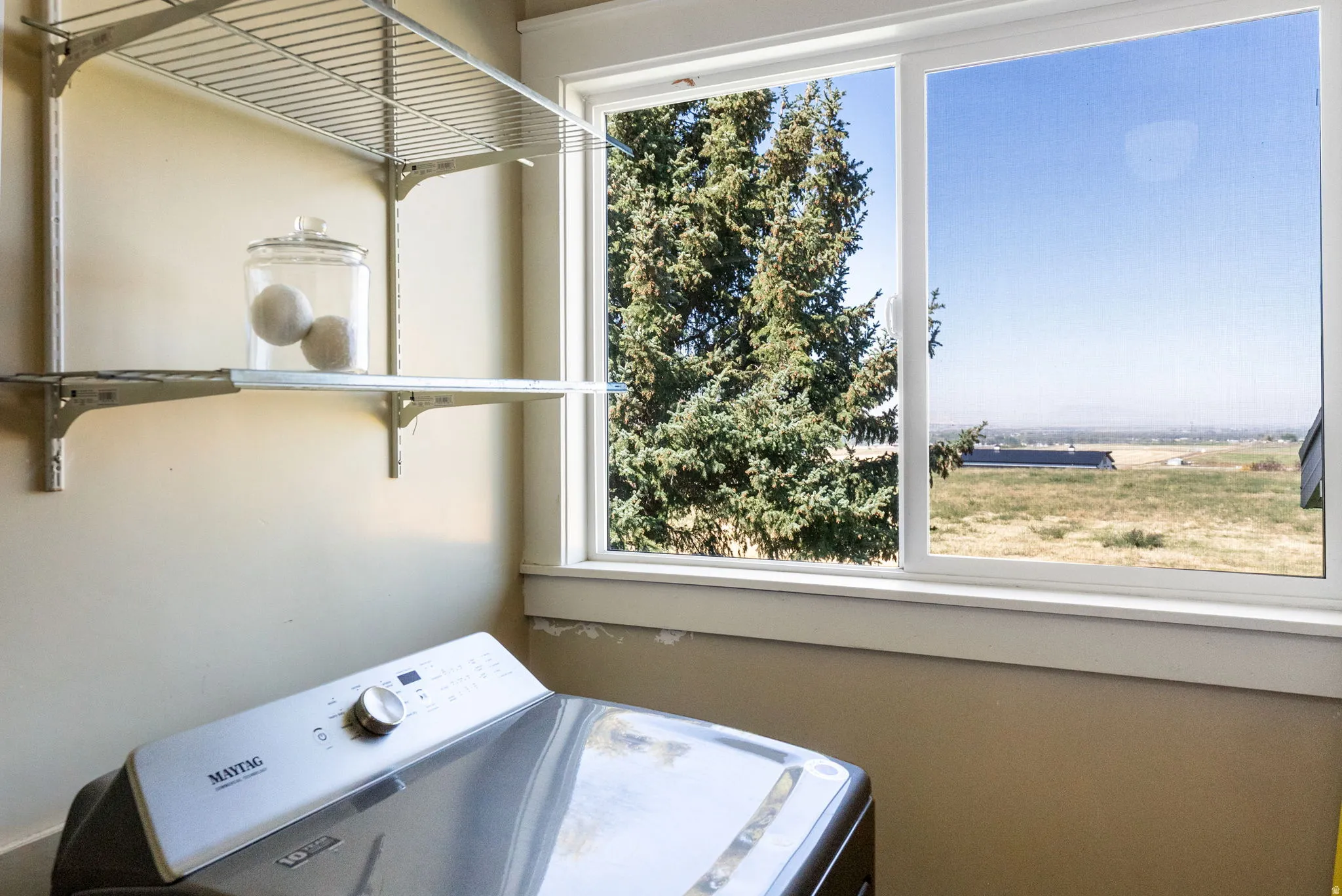 Slider window with a distant landscape, wire shelving, and a neutral wall finish