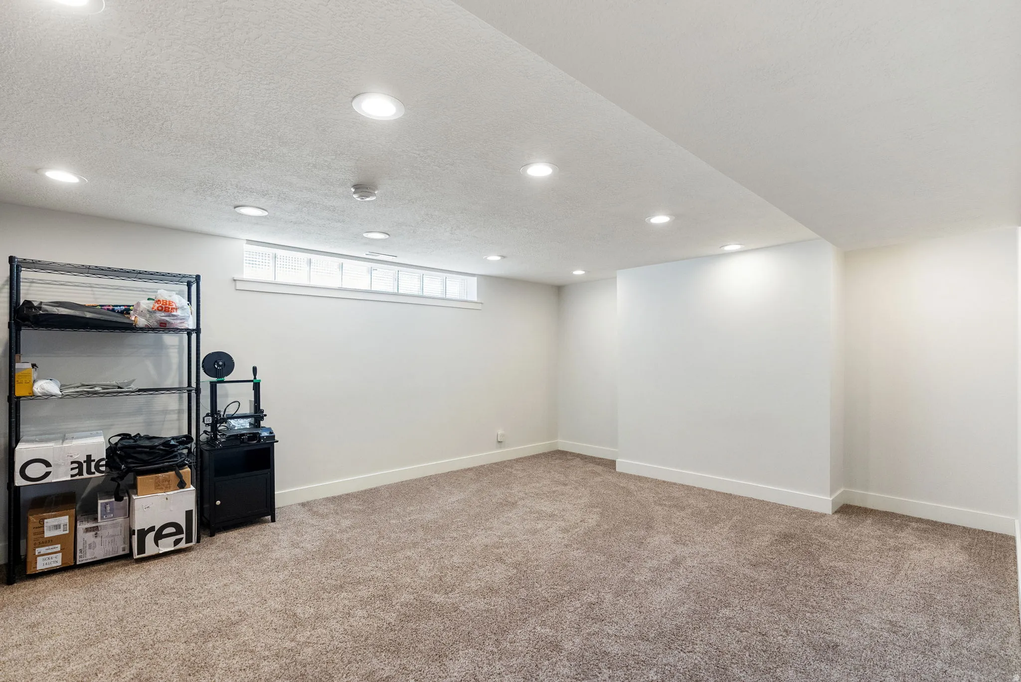 Recessed lighting, light-colored carpeting, white walls, and a horizontal window