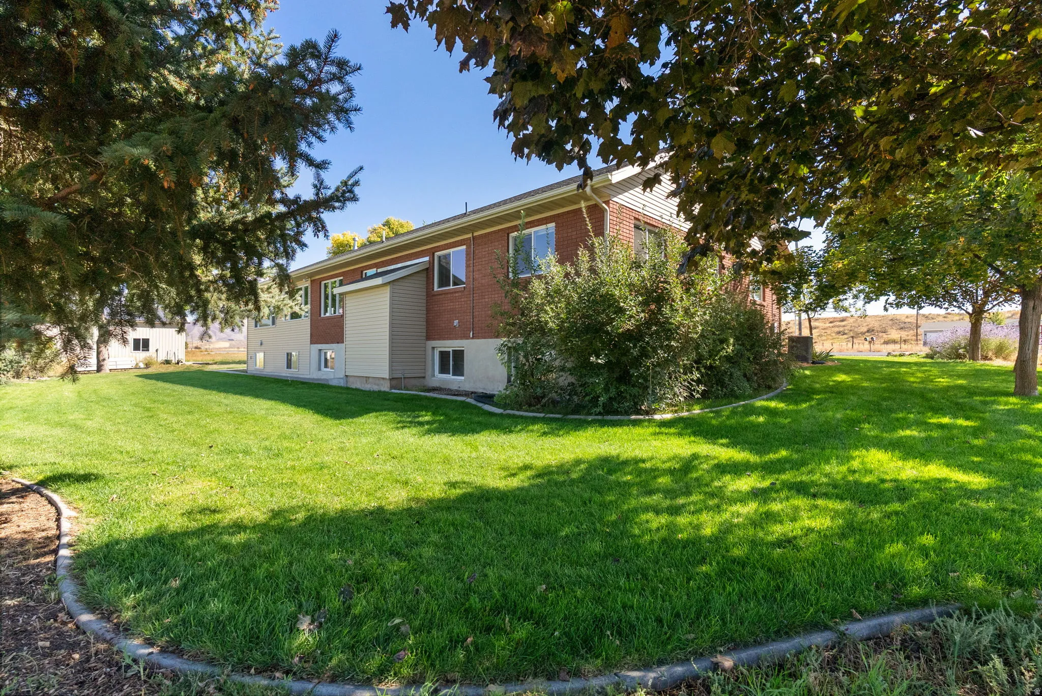 Expansive green lawn with mature trees and established landscaping