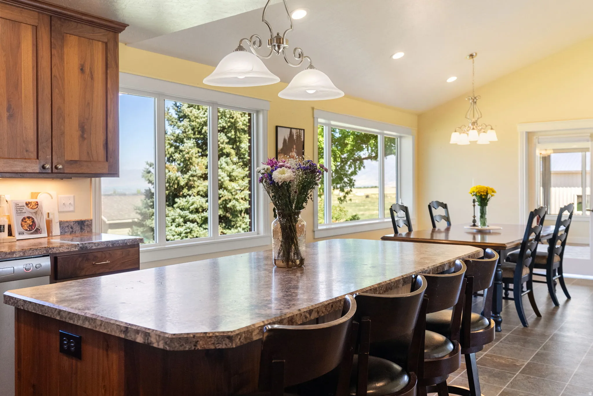 Kitchen featuring wood cabinetry, an extended island with a stone-finish countertop, and recessed lighting