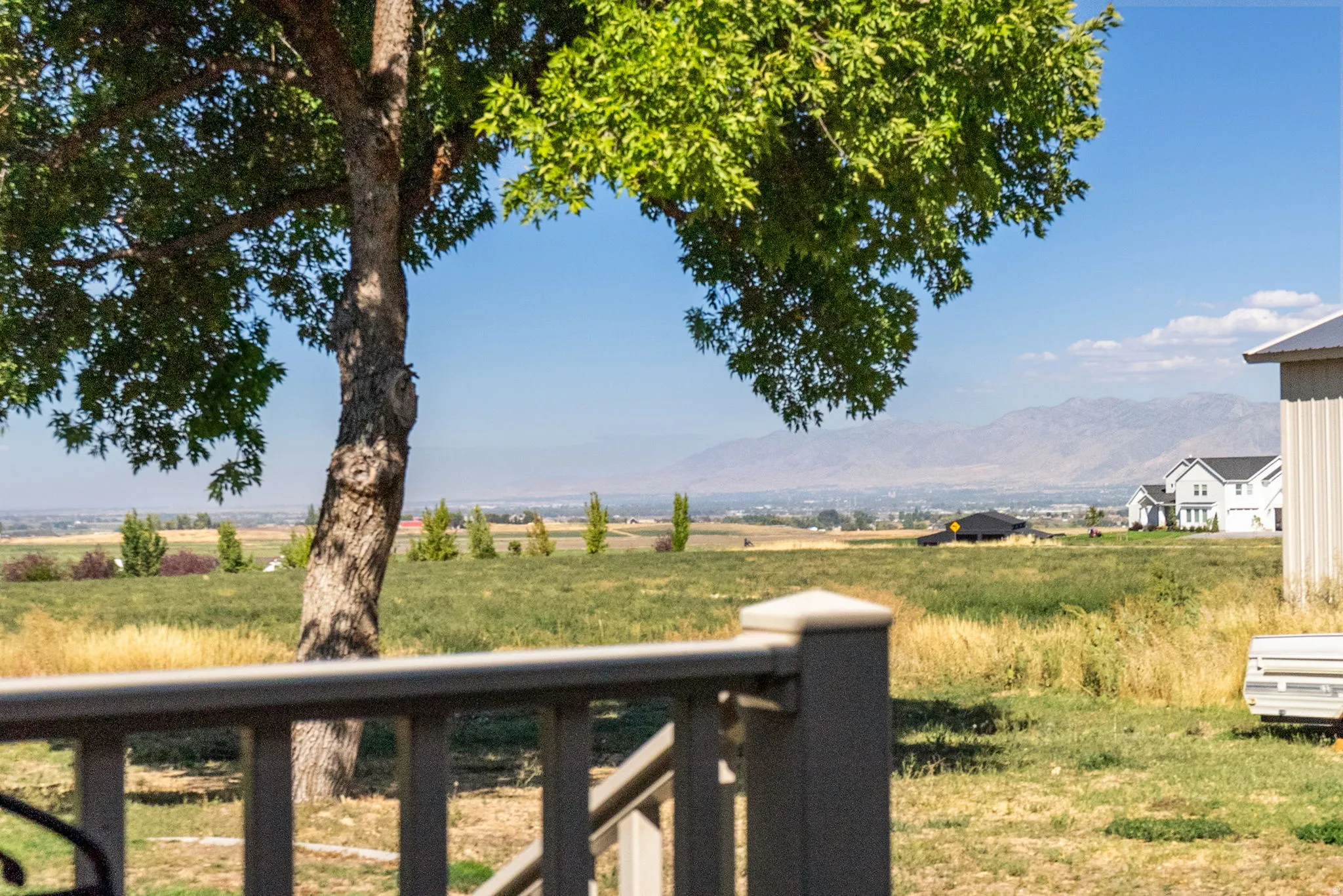 Expansive outdoor space featuring a mature tree, natural landscaping, and distant mountain scenery