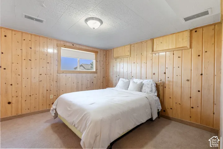 Knotty pine wood paneling, carpet flooring, window with exterior scenery, ceiling-mounted light fixture, and textured ceiling