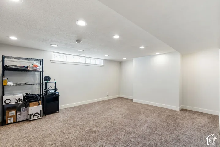 Recessed lighting, light-colored carpeting, white walls, and a horizontal window