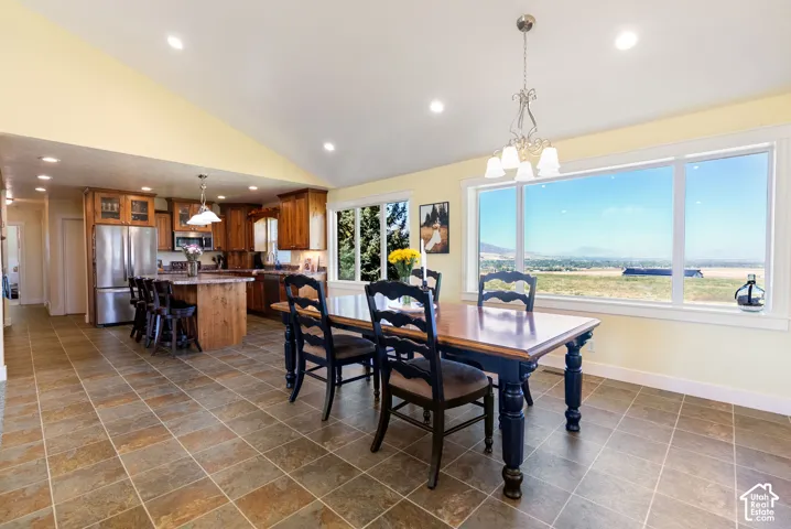 Vaulted ceiling, recessed lighting, tile flooring, kitchen island with seating, and large windows