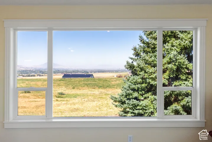 Expansive picture window with white trim, offering a broad scenic backdrop with distant mountains and a prominent evergreen tree