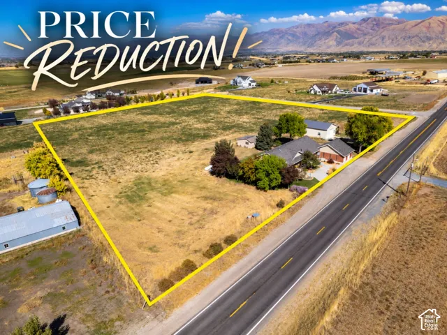 Expansive acreage featuring a multi-structure property, mature trees, and a mountain backdrop