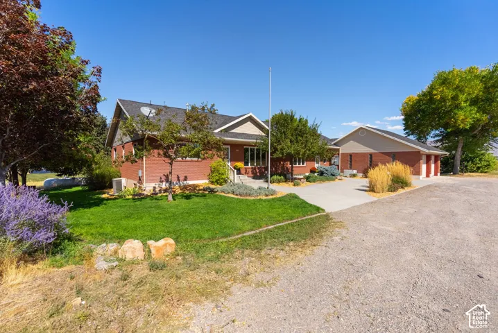 Brick exterior with an attached garage, paved driveway, and established landscaping