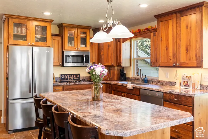 Kitchen featuring wood cabinetry, stainless steel appliances, a center island with seating, and recessed lighting