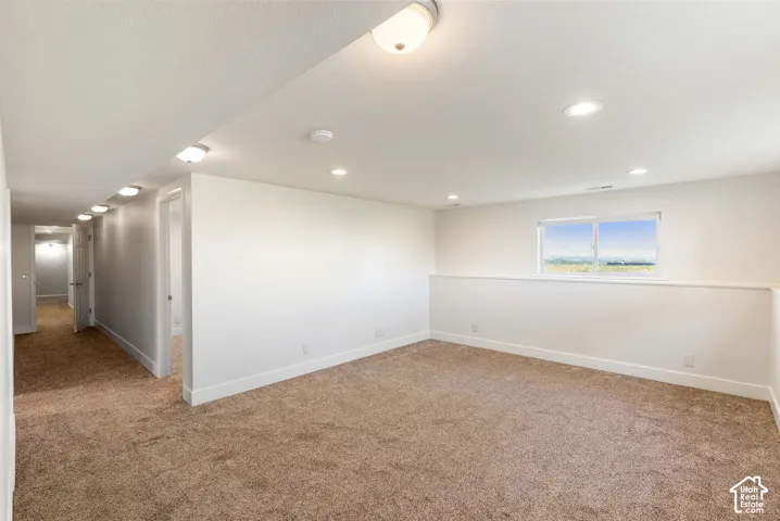 Recessed ceiling lighting, window with exterior scenery, two-tone wall paneling, and neutral-toned carpeting
