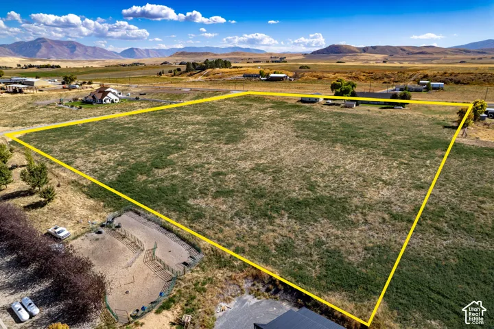 Expansive open land with a mountainous backdrop, featuring a defined property boundary and surrounding rural landscape